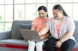 © offsuperphoto - mother using laptop computer with a girl down syndrome or her daughter, smiling and enjoying on sofa