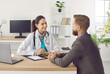 © Studio Romantic - Friendly female doctor talks to her patient about his diagnosis while sitting together at table in office of clinic. Man came to clinic for consultation. Healthcare and medicine concept.