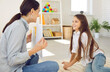 Professional therapist talking to happy child. Little girl having fun during lesson with private tutor or appointment with psychologist. Female English language teacher showing pictures to smiling kid