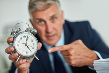 The Clocks Ticking. Portrait Of A Mature Businessman Gesturing Toward A Clock In Frustration.