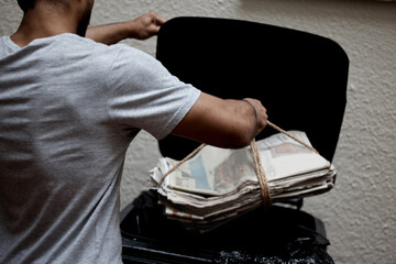 Poster - Organisation is key. Shot of a young man putting newspaper in the bin to be recycled.