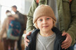 © Seventyfour - Close up of Caucasian young boy with dad looking at camera at help center for refugees, copy space