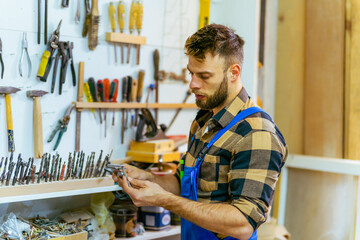 Bearded caucasian carpenter checking and measures drills