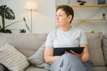 Canvas Print - people, technology and internet concept - happy middle aged woman with tablet pc computer at home.