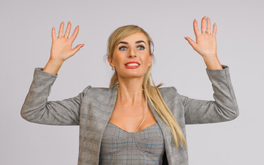 Wall Mural - business woman in a gray suit happily waving two hands with an open palm, half-length portrait on a white background