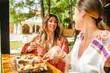 two women caucasian female friends tasting food and white wine at the table on the party in summer day on vacation - selective focus real people copy space