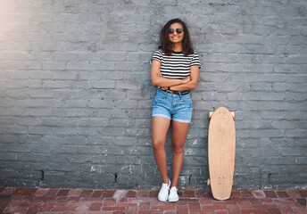 Wall Mural - Im a skater girl for sure. Portrait of a young woman standing with a skateboard against a grey wall.