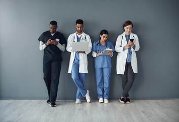 This is actually our lunch break. Shot of a group of doctors standing against a grey background at work.