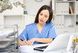 © JackF - Skillful woman physician sitting at table in her office and writing.