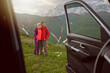 Happy couple hugs on beautiful nature mountains area out of car 