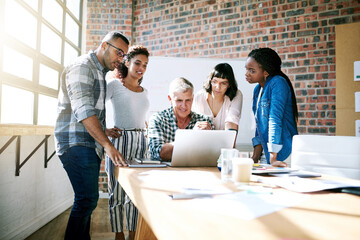 Wall Mural - Im impressed with the traffic it brings to our business. Shot of a group of colleagues using a laptop together in a modern office.