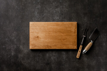 Wall Mural - Chopping board and vintage knife, fork on dark concrete tabletop. Kitchen background copy space