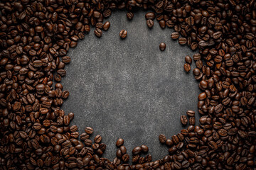 Wall Mural - Coffee frame on stone background. Roasted beans scattered with round copy space in center