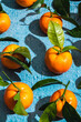 © ADDICTIVE STOCK - Crop of tropical tangerines with leaves on blue surface