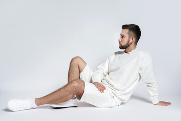 Wall Mural - Handsome man wearing white sweatshirt and shorts with wireless earbuds sitting