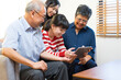 © bennnn - Smiling Asian grandparents on couch with granddaughter looking at tablet. happy three generation family spending time together at home.