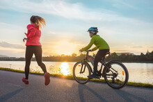 Happy Mother And Son Go In Sports Outdoors. Boy Rides Bike In Helmets, Mom Runs On Sunny Day. Silhouette Family At Sunset. Fresh Air. Health Care, Authenticity, Sense Of Balance And Calmness