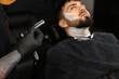 © New Africa - Professional hairdresser working with bearded client in barbershop, closeup