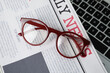 © New Africa - Newspaper and glasses on laptop, top view