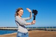 © Valerii Honcharuk - Middle-aged woman recording video on smartphone with outdoor on seashore