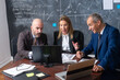 © KAMPUS - Friendly business group working in office. Two men and pretty woman looking at computer feeling surprised of good tendency with prices on stock exchange. Financial analytics, business growth concept
