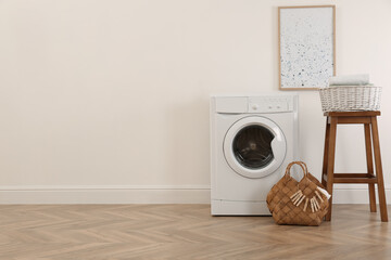 Poster - Laundry room interior with modern washing machine and wooden stool near white wall. Space for text