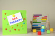 Magnetic board with phrase ABA Therapy, colorful numbers and abacus on white wooden table