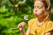 © bondarillia - Adorable little girl blowing on a dandelion on a sunny summer day