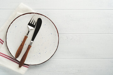 Wall Mural - Ceramic empty white plate. Rustic vintage set of white plate, wooden spoon on light white wooden background. Vintage zero waste silverware. Empty dishes. Top view. Mock up.