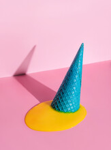 An Overturned Waffle Cone With Melted Ice Cream On A Pink Background.
