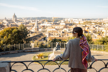 Wall Mural - Woman enjoying beautiful morning cityscape of Rome, walking in Villa Borghese Park. Old fashioned woman wearing coat with colorful shawl in hair. Concept of italian lifestyle and travel