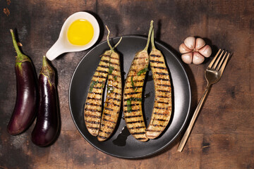 Wall Mural - Grilled eggplants in black plate on wood background.