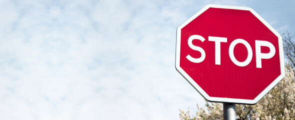 Stop sign against a bright blue sunny summer sky. With space for your text. Close up. Banner