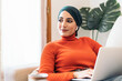 © ADDICTIVE STOCK - Muslim woman with laptop resting on couch