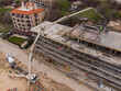Pouring concrete cement on the roof of residential building under construction using a concrete pump truck machine with high boom to supply the mixture to the upper floors. Aerial view.