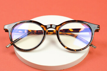 Stylish women's glasses in a leopard-colored frame on a white plaster podium