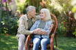 © Prostock-studio - Happy elderly couple enjoying time in countryside, woman sitting in wicker chair and man embracing wife