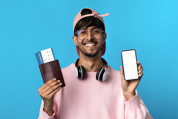 Indian guy holding smartphone with empty screen, passport and tickets