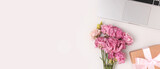 Banner with laptop, bouquet of eustoma flowers and gift box with tied bow on a gray background. Online celebrate concept, present for Mothers Day with copyspace.