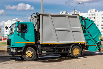 Fototapete - An automobile garbage truck collects garbage in residential areas of a modern city. Close-up of a car for collecting and transporting garbage.
