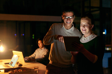 Leinwandbilder - All they need packed into one handy device. Shot of businesspeople working together on a digital tablet in an office at night.