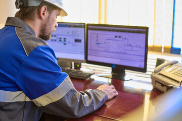 Worker in overalls uses a linear telemechanics system to control the technological processes of the enterprise. Automated workplace of a dispatcher or operator of a modern enterprise