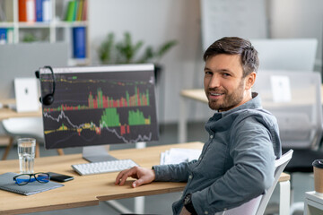 Aufkleber - Mature man working on computer in office and smiling at camera, monitor with graphics and charts