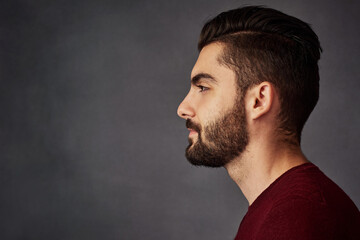 Canvas Print - Handsome from every angle. Studio shot of a handsome young man posing against a dark background.