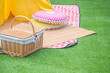 Vintage wicker basket with mat and pillows on artificial green grass for picnic and recreation time
