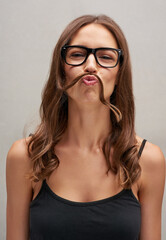 Canvas Print - Looks like its Movember again. Studio portrait of an attractive young woman posing with her hair over her lip against a grey background.