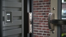 Man in a suit is standing outside of the main entrance of the  building and he touches a multi-button key fob to a keyless entry system to gain entry into the building. Shallow DOF focus on the fob