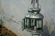 Two old metallic lanterns with burnt candles inside hanging against a grungy wall facade