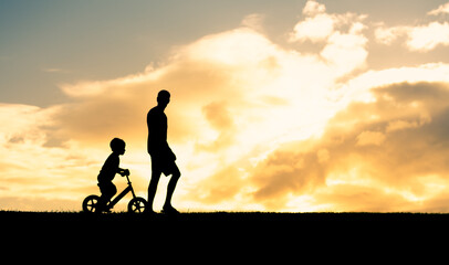 Wall Mural - Father son going for a walk riding bike at sunset. 