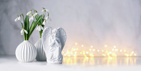 angel and snowdrops flowers on table, light abstract background. Religious church holiday. symbol of faith in God, Christianity. Feast of Annunciation to the Blessed Virgin Mary. banner. copy space